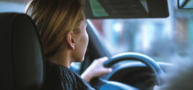 a woman sitting in a car with a steering wheel by Jan Baborák courtesy of Unsplash.